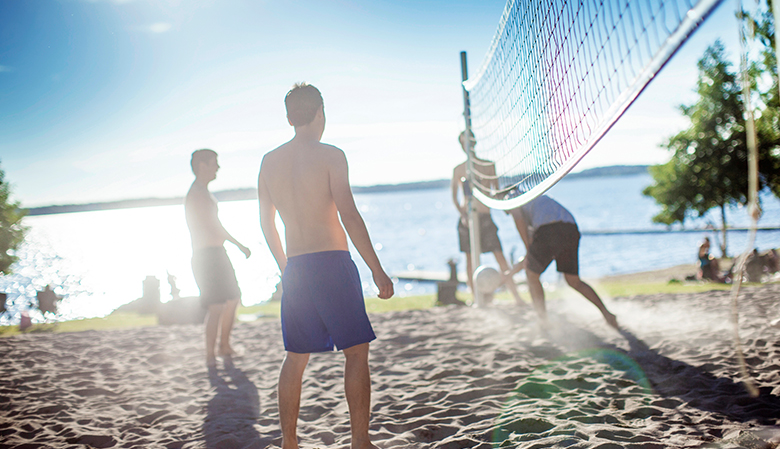 Barn på strand vid beachvolleyboll-nät