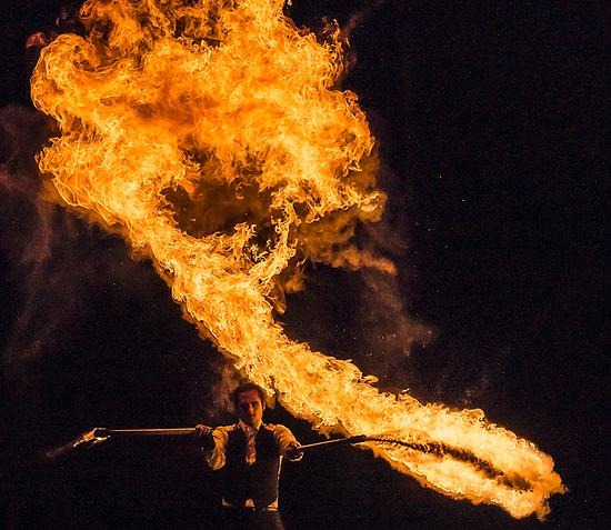 Bild på en man som jonglerar med eldstavar.