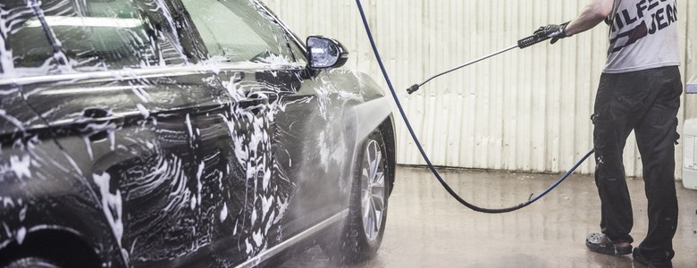 Man tvättar bil med högtryckstvätt.